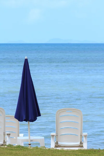 Vista al mar con sombrilla azul y sillas blancas — Foto de Stock