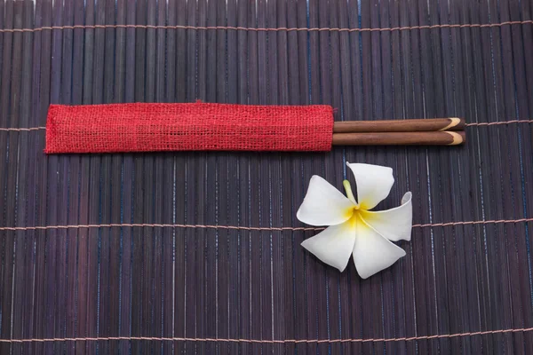 Chopsticks and white frangipani plumeria flower — Stock Photo, Image