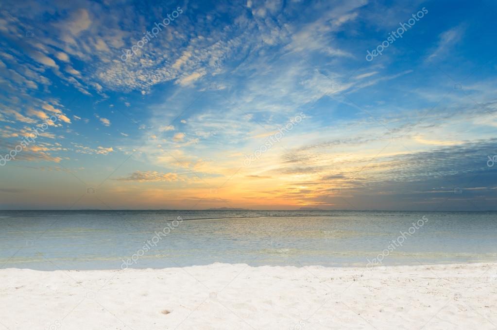 Dramatic sky sea and white sand beach at dawn