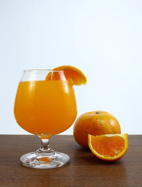 Vaso de zumo de naranja y rodajas sobre tabla de madera —  Fotos de Stock