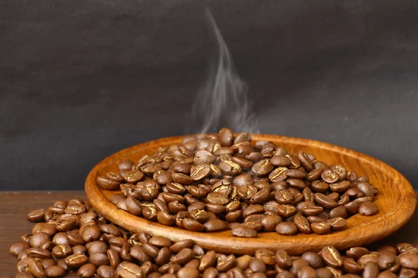Granos de café en plato de madera con fondo grunge —  Fotos de Stock