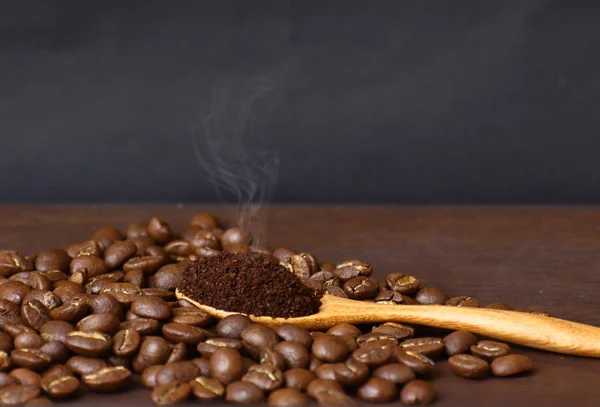Granos de café y café molido en cuchara de madera con respaldo grunge — Foto de Stock