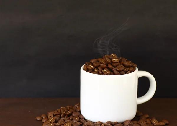 Chicchi di caffè in tazza bianca su tavola di legno in stile vintage — Foto Stock