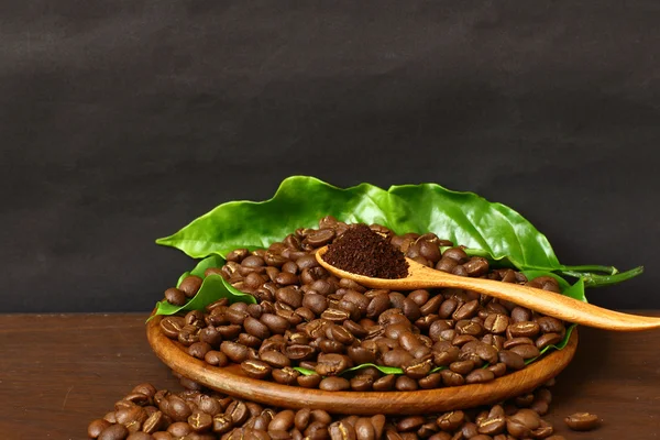 Fagioli di caffè e loro foglia su cucchiaio di legno — Foto Stock