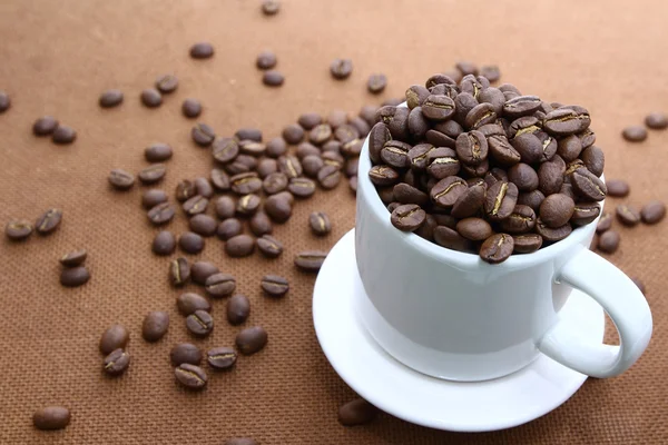 Coffee bean v bílých cup na dřevěné desce — Stock fotografie