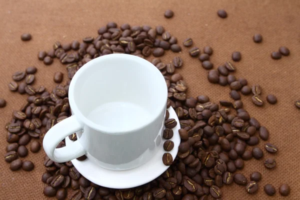 Coffee beans and white cup on wooden board — Stock Photo, Image