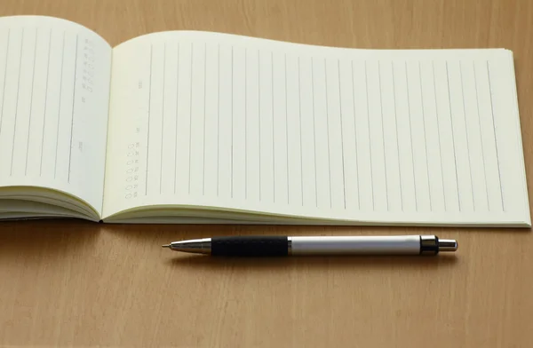 Caderno de caneta e plano de negócios em mesa de madeira — Fotografia de Stock