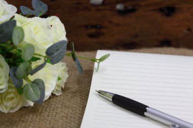 Gül çiçek ve üstünde çul defter ile natürmort