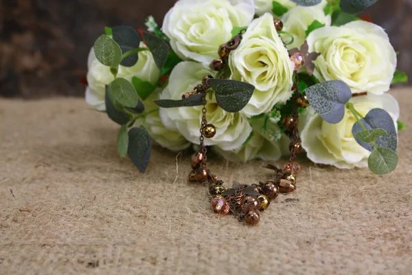 Still life with rose flower and bronze nacklace on sackcloth — Stock Photo, Image