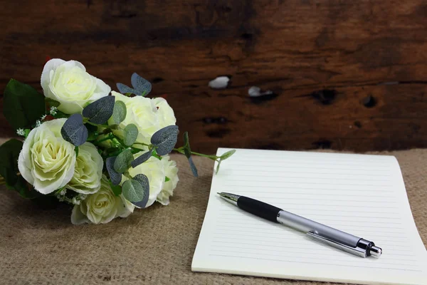 Bodegón con flor de rosa y cuaderno sobre tela de saco — Foto de Stock