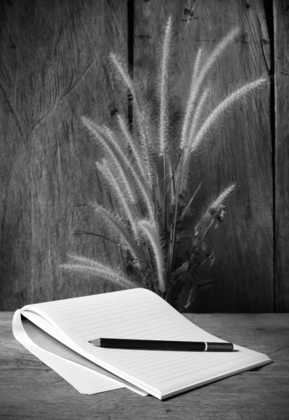 Černé a bílé notebooky s květ luční trávu na dřevěné pozadí — Stock fotografie