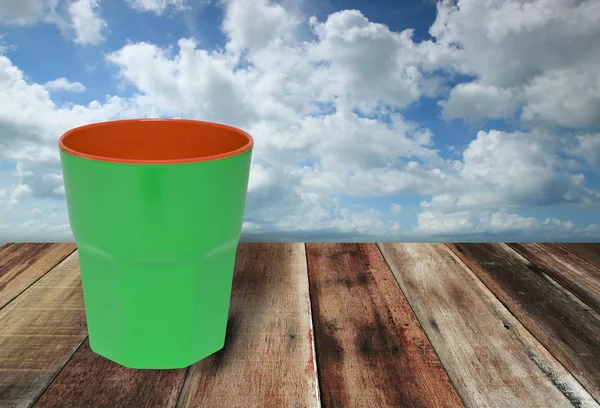 Green cup on grunge wood floor — Stock Photo, Image