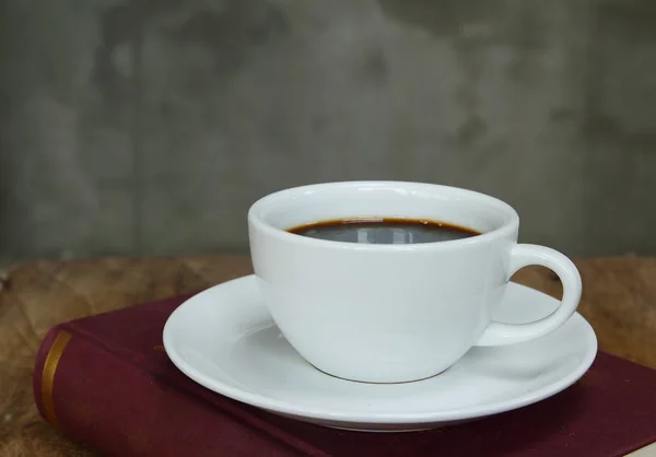 Stilleben med kopp kaffe och bok om grunge bord av trä i vintage stil — Stockfoto