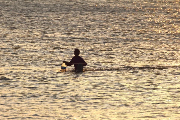 Silueta de pescador joven en el océano al atardecer — Foto de Stock