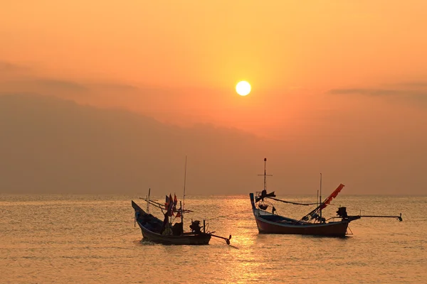 Forbløffende gyllen solnedgang over havet og himmelen med fiskebåt flytende – stockfoto