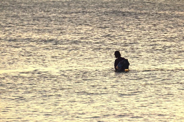 Silhouette eines jungen Fischers im Meer bei Sonnenuntergang — Stockfoto