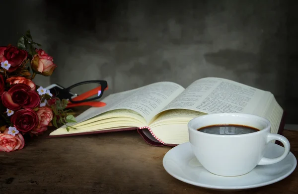Чашка кофе, розы и книга на старом деревянном столе — стоковое фото