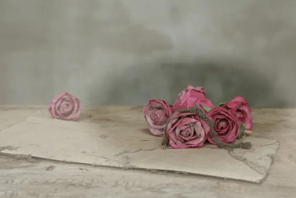 Old paper pink roses on grunge wood table — Stock Photo, Image