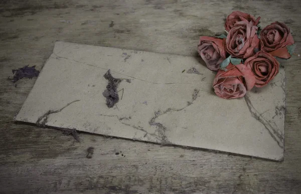 Vintage old paper pink roses on grunge wood table — Stock Photo, Image