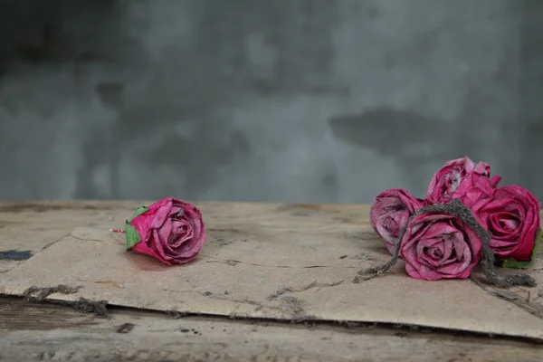 Vintage old paper pink roses on grunge wood table