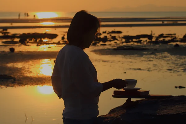 Silueta mujer sosteniendo café al atardecer del paisaje marino — Foto de Stock