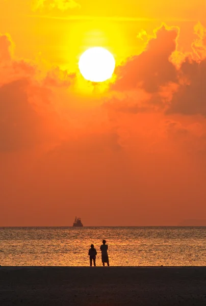 Älskare ser solnedgången med gyllene ljus över stranden — Stockfoto