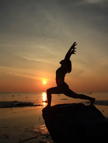 Силуэт девушки йоги на пляже на восходе солнца делает High Lunge Pose — стоковое фото