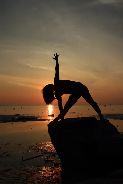 Silhouette yoga girl by the beach at sunrise doing Triangle Pose — Stock Photo, Image