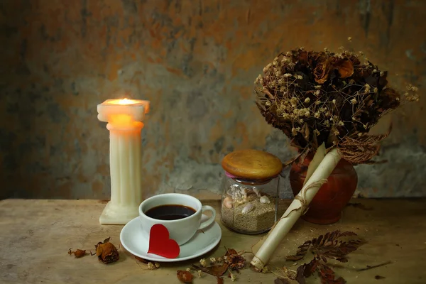 Still life cup of love,candle, dry roses and grunge paper on wooden table — Stock Photo, Image