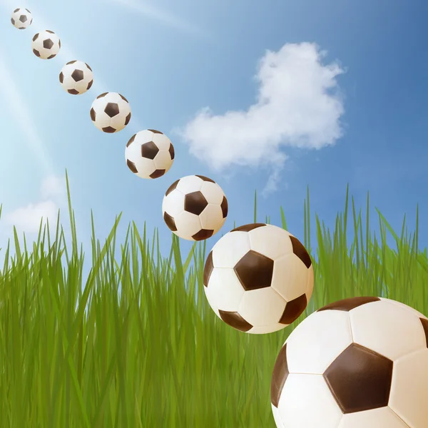 Футбольный мяч на зеленой траве и голубое небо с облаком формы сердца — стоковое фото