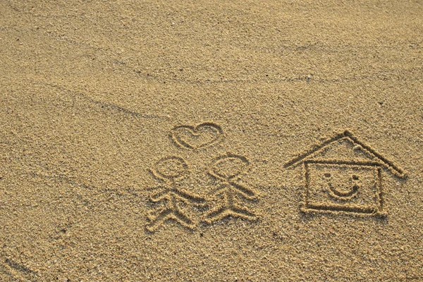 Feliz amante y casa con forma de corazón dibujado en la arena de la playa — Foto de Stock