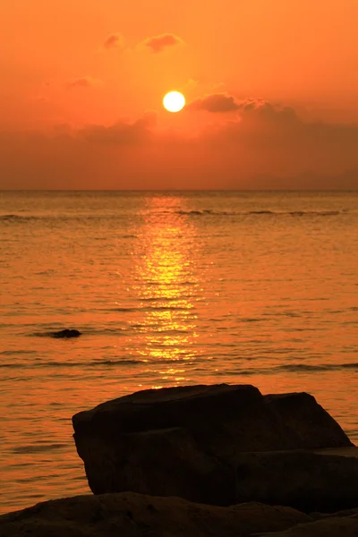 Rock na praia com o pôr-do-sol vermelho céu fundo do mar — Fotografia de Stock