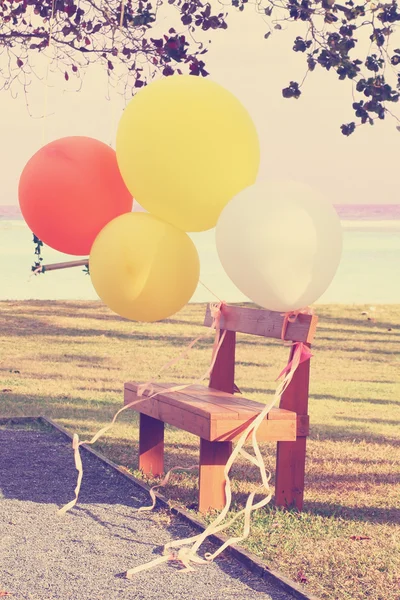 Globos coloridos y silla de madera — Foto de Stock