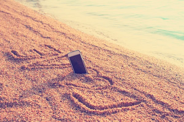Telefoon op strand met liefde tekst — Stockfoto