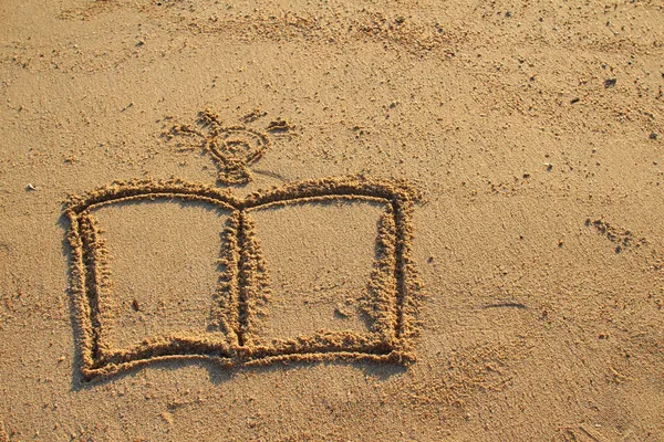 Book and light bulb drawn on sand — Stock Photo, Image