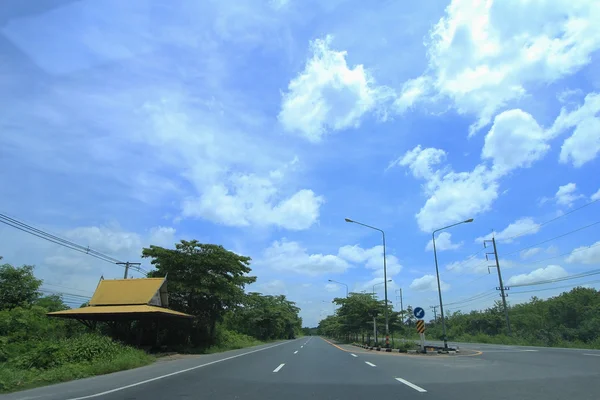 Estrada no campo com fundo azul céu — Fotografia de Stock