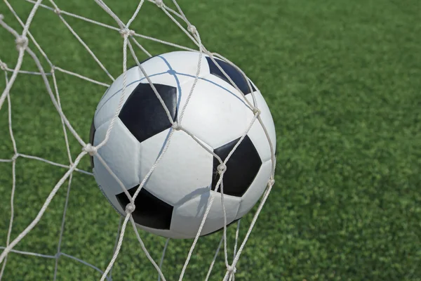 Soccer ball in goal and green grass field — Stock Photo, Image