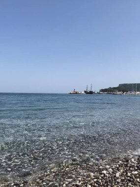 Deniz kıyısında çakıl taşları, deniz arka planı. Bir deniz dalgası sabahın erken saatlerinde çakıl taşı plajını yıkar. Yakın plan. Kemer, Türkiye