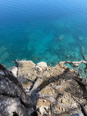Denizden yükselen kayalar, mavi gökyüzü, mavi deniz. Sahildeki kayaların ve denizin güzel manzarası.