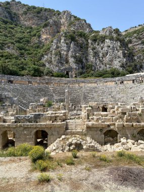Tarihi Taş, Myra antik şehrinde bas rahatlama ve antik tiyatro ile karşı karşıya. Lycia, Demre, Antalya, Türkiye 'de taş kesimi mezarlar harabe. Lycia kaya kesiminin mezarlarının arkeolojik kalıntıları