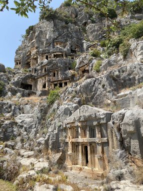 Tarihi Taş, Myra antik şehrinde bas rahatlama ve antik tiyatro ile karşı karşıya. Lycia, Demre, Antalya, Türkiye 'de taş kesimi mezarlar harabe. Lycia kaya kesiminin mezarlarının arkeolojik kalıntıları