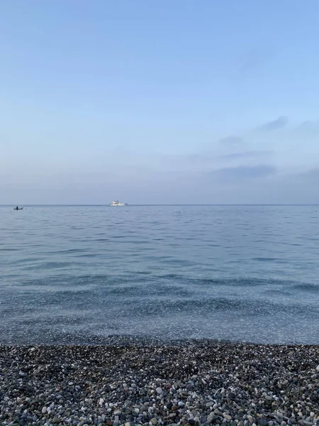 Deniz kıyısında çakıl taşları, deniz arka planı. Bir deniz dalgası bir çakıl taşı plajını yıkar. Antalya ilinin Kemer ilçesine bağlı Akdeniz kıyısındaki sahil manzarası