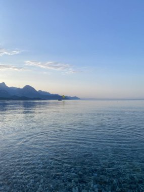 Deniz kıyısında çakıl taşları, deniz arka planı. Bir deniz dalgası bir çakıl taşı plajını yıkar. Antalya ilinin Kemer ilçesine bağlı Akdeniz kıyısındaki sahil manzarası