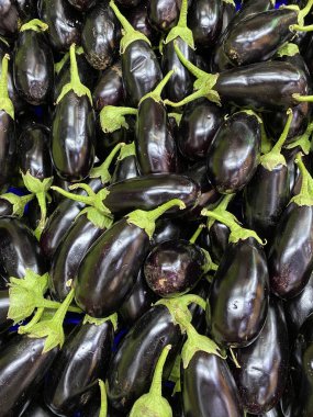 Meyve sebze pazarında bir yığın taze patlıcan, yerel üreticilerin organik ekolojik gıdaları yakın mesafede.