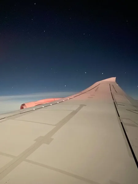 Travelling by air plane, looking through plane window enjoying beautiful night sky full of stars and milky way