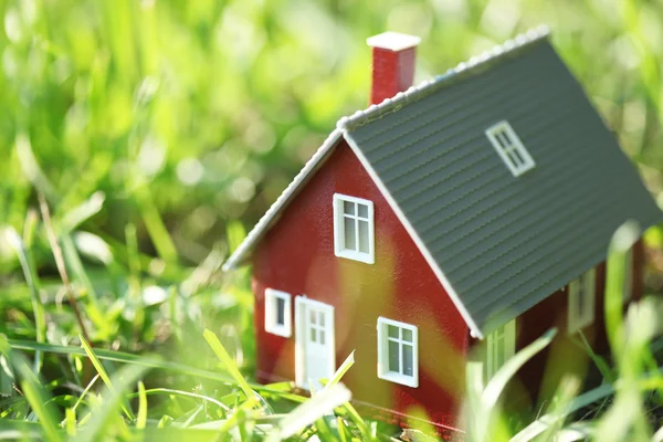 Casa vermelha minúscula na grama verde — Fotografia de Stock