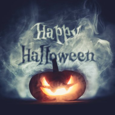 Cadılar Bayramı 'nın ürkütücü Jack o fener kabağı oyulmuş korkunç sırıtan yüzüyle Cadılar Bayramı gecesi dumanında parlayan Cadılar Bayramı mesajıyla.