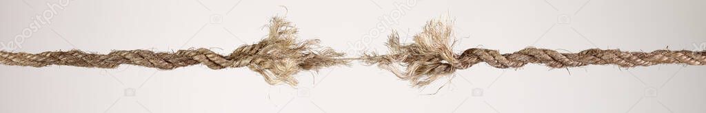 Long dirty rope, frayed at both ends and ready to break apart with rope held together by a last strand ready to snap. Concept of dangerous stress or stressful situation like divorce separation, deadlines, failure, or tension.