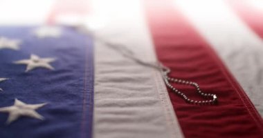Parlak askeri künyeli Amerikan bayrağının yavaş çekimleri. Silahlı Kuvvetler Günü, Anma Günü, Gaziler Günü, 4 Temmuz ya da diğer vatansever ABD bayramları için arka plan.