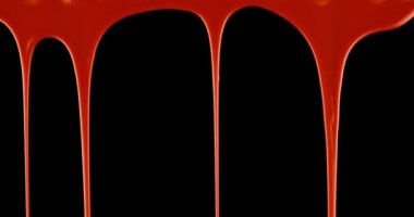 Spooky steady drip of bright red blood pouring over black background.